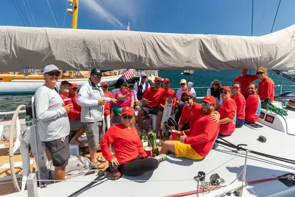 A sailing crew in red Mount Gay shirts and caps gathered on the deck of a yacht at a US regatta.